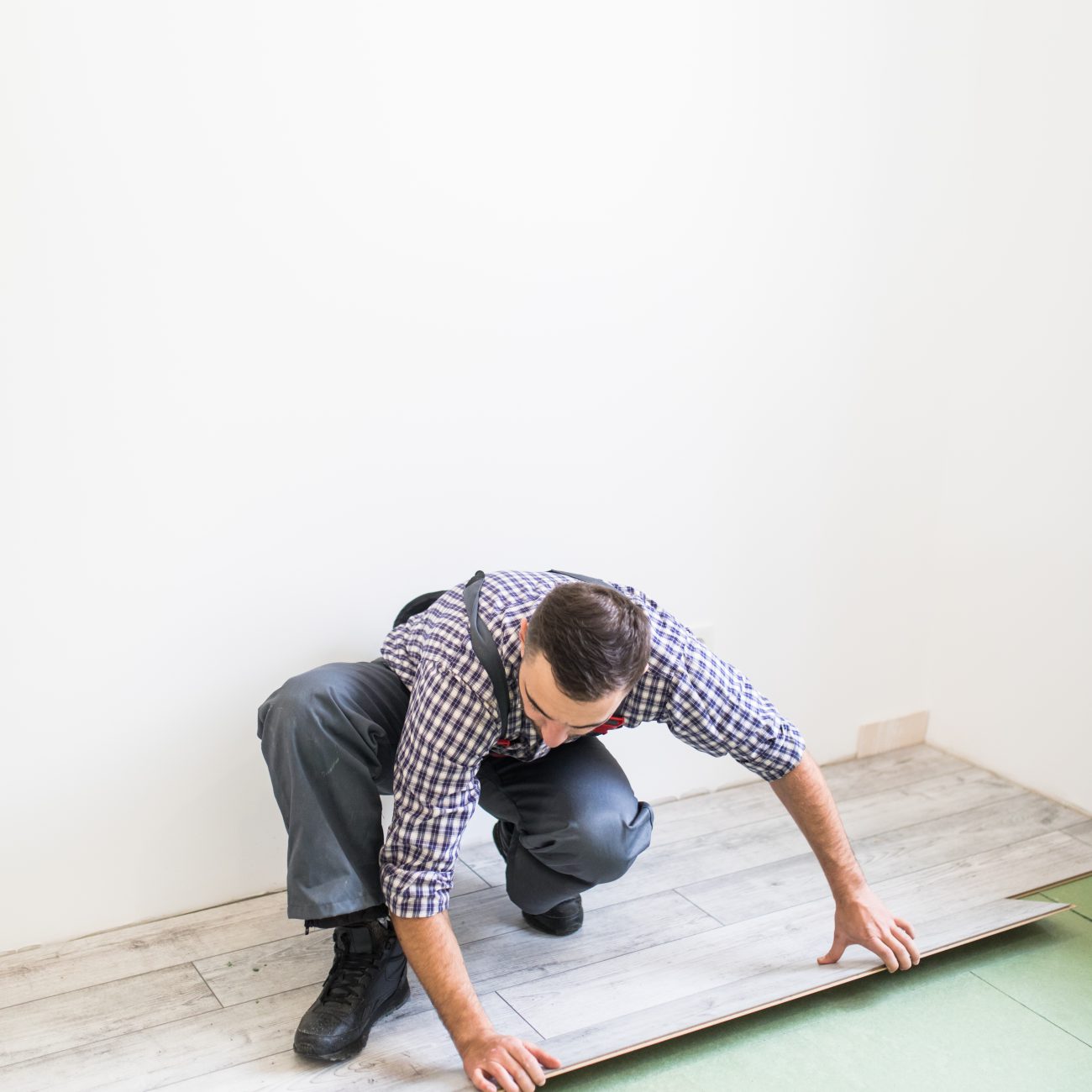 Young worker laying a floor with bright laminated flooring boards